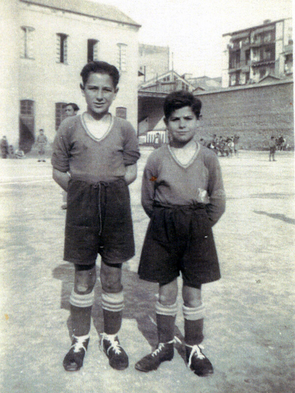 Dos internos con uniforme de futbol. Al fondo se ven los lavabos del patio de la Casa de la Misericordia de Valencia. 1946-47